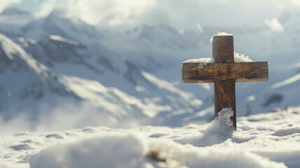 Small wooden Christian cross in middle of snow and snowy mountains in background and copy space