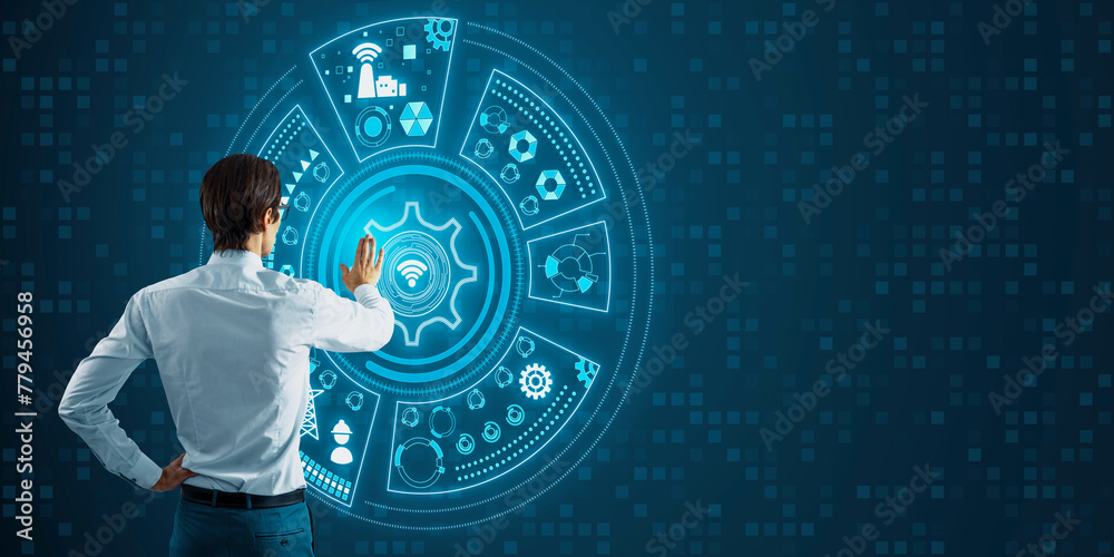 Poster Back view of young businessman pointing at round digital cogwheel and other icons hologram on blue background with mock up place. Tech support and innovation concept.