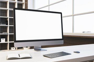 Close up of designer office desktop with empty white computer monitor, window with city view and wooden shelves in the background. Mock up, 3D Rendering.