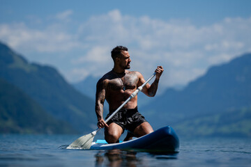 Sexy man with paddle board. Man paddling on paddleboard. Muscular strong Hispanic man on sup board...