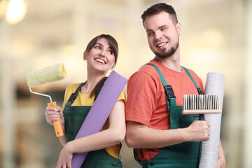 Workers with wallpaper rolls and tools indoors