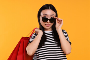 Beautiful woman with shopping bags on yellow background