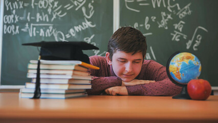 A high school student sleeps on a desk in the classroom.