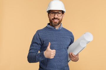 Architect in hard hat with drafts showing thumbs up on beige background