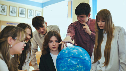 Students look at a globe of the starry sky in a classroom at school. - obrazy, fototapety, plakaty