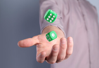 Man throwing green dice on grey background, closeup