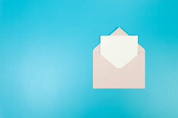 Top view of light pink envelope, white card on blue background. Post flat lay. Copy space.