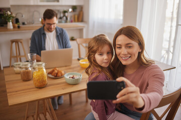 Mother and daughter taking Selfie with smart phone during breakfast at home