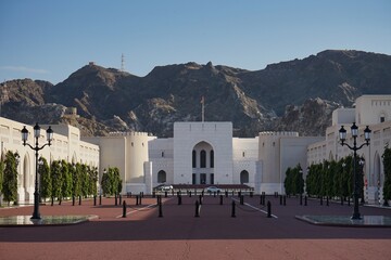 Grand entryway to Al Alam palace, with the stunning Hajar mountains cascading over the plaza, during sunset in Muscat, Oman