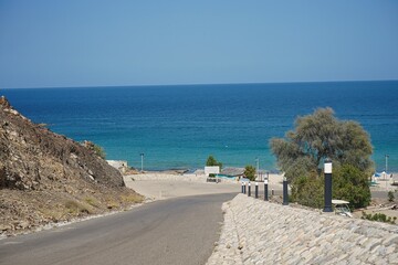 Steep cobblestone road leading down to the beaches and bright turquoise blue seas of the Persian Gulf outside of Muscat, Oman