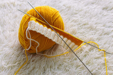 Yellow knitting yarn and knitting needles. Knitwear fashion. Wool socks and needles. Knitting hobby. Handcraft clothing. Needlework concept. Wool knitted socks. Homemade crochet footwear. - 779469559