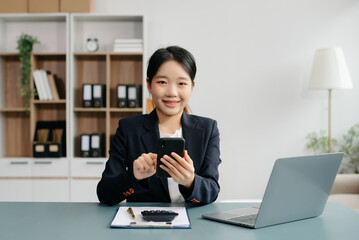 Young beautiful woman typing on tablet and laptop while sitting at the working white table