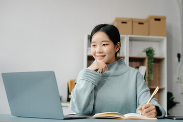 Confident Asian woman with a smile standing holding notepad and tablet at the office.