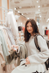 Korean teenage girl holds a credit card in her hands and wants to pay for new clothes in a shopping mall. Retail and consumerism. Sale promotion and shopping concept. Part of a series - 779471196