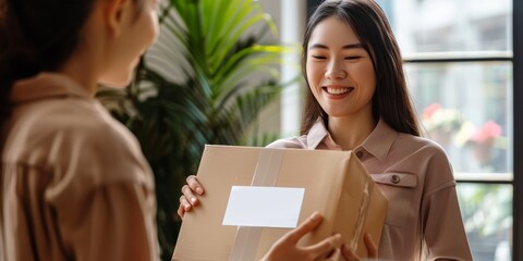 A woman is holding a brown box and smiling at another woman