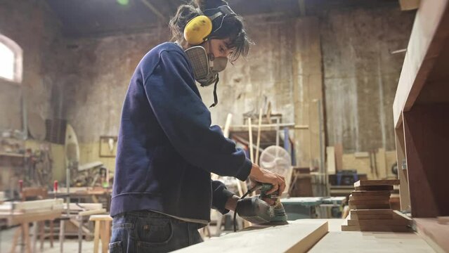 Woman carpenter sanding wood block. Feminist girl process timber bar. Male carpentry work skill. Female joiner woodwork. Feminism worker. Person use sander tool. Diy master class workshop. Job project