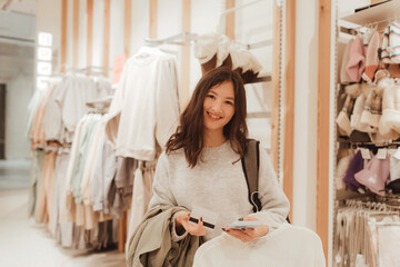 Korean teenage girl holds a credit card in her hands and wants to pay for new clothes in a shopping mall. Retail and consumerism. Sale promotion and shopping concept. Part of a series - 779472170