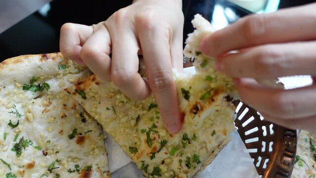 Hands eating garlic naan dip bread in to Indian curry South Asia food