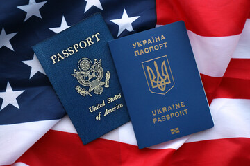 Passport of Ukraine with US Passport on United States of America folded flag close up