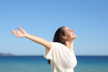 Happy woman laughing outstretching arms on the beach