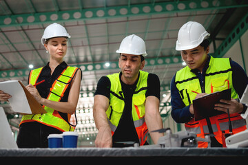 Three construction workers are standing around a table, looking at a laptop