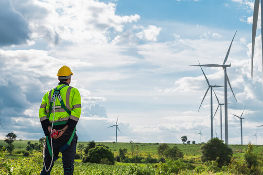  man in a yellow helmet stands in a field of wind turbines