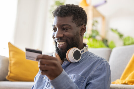 Smiling non-binary person making payment through credit card at home