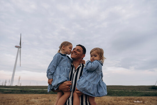 Girl kissing father standing at wind farm