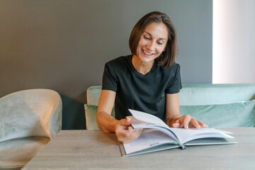 Happy businesswoman turning pages of magazine in cafe