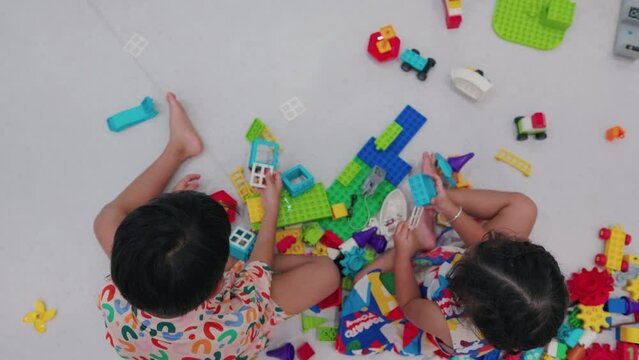 Adorable asian kid boy and girl enjoying building toy block learnning construction game