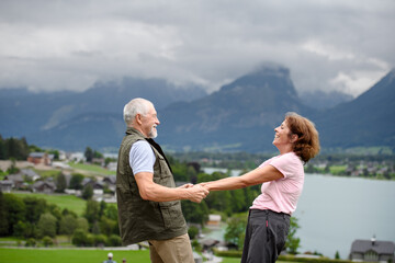 Fototapeta na wymiar Active elderly couple on trip together, during spring day. Senior tourists visiting, exploring new places. Side view, holding hands.