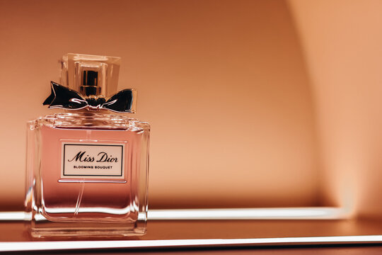 Miss Dior luxury glass bottle perfume on a stand with golden bokeh light. It was founded in 1946 by French fashion designer Christian Dior.