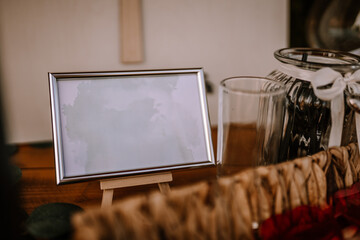 Fototapeta na wymiar Valmiera, Latvia - Augist 13, 2023 - A blank sign in a frame on an easel with a glass jar and silverware in the background...
