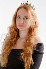 Young red-haired woman wearing a crown on a light background - 779495150