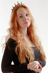 Young red-haired woman wearing a crown on a light background - 779495152