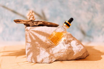 A mock-up of a transparent bottle of cosmetics with a pipette on a pumice stone. A bottle of...