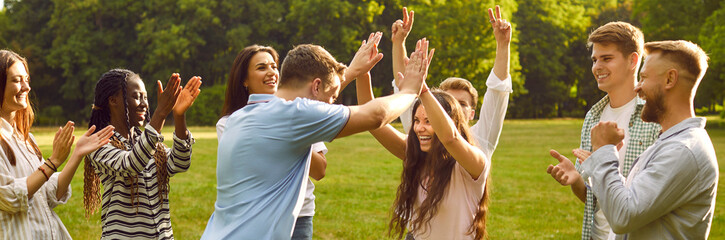 Group of happy diverse people celebrate victory in outdoor team game in green summer park. Joyful...