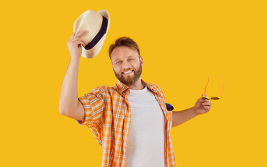 Portrait of a smiling man in summer attire, joyfully removing hat in greeting against an orange...