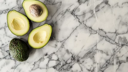 Tuinposter Avocado halves with pit on marble countertop, minimalist and sophisticated, highlighting creamy texture and rich green color.  © Aleksandra