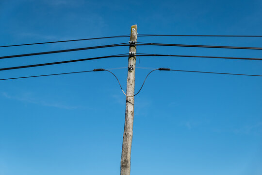 Poste de madeira de suporte para os cabos telefónicos em meio a um céu azul