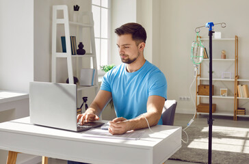 Young man sitting and working on a laptop at the desk of his workplace at home or in office while...