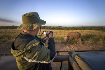 tourist photographs a wild leopard during a safari tour in Kenya and Tanzania. Concept Travel and...