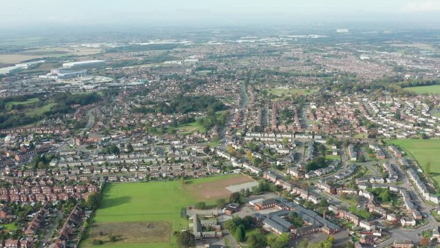Aerial footage above a typical housing estate in the UK, showing businesses, rows of houses and roads with traffic, taken in Castleford in Leeds West Yorkshire UK