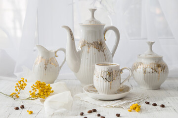 Modern still life with a coffee set and a spring mimosa branch on a light windowsill