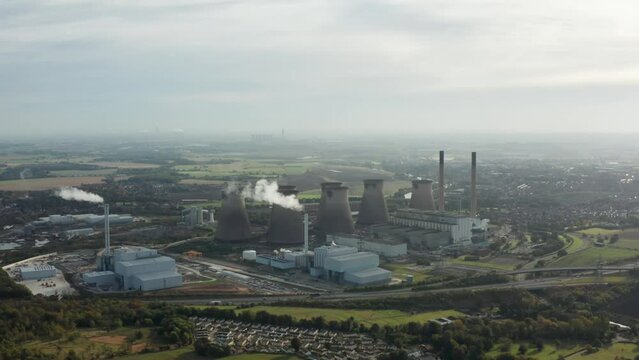 Aerial footage of the town of town of Ferrybridge in Wakefield West Yorkshire in the UK showing a power stations cooling towers, taken with a drone on a part cloudy day in the winter time
