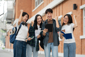 Happy group of college students use laptop feel excited overjoyed triumph with good news over...