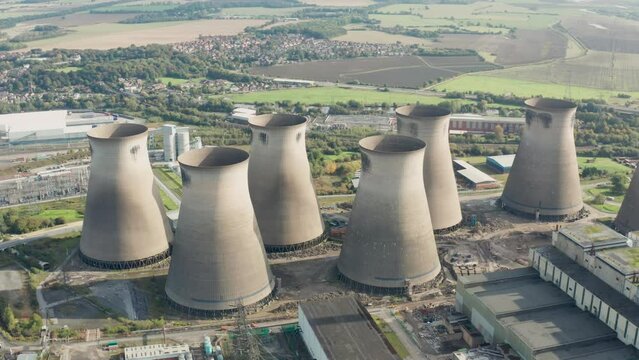 Aerial footage of the town of town of Ferrybridge in Wakefield West Yorkshire in the UK showing a power stations cooling towers, taken with a drone on a part cloudy day in the winter time