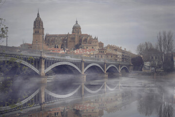 iglesia y puente de salamanca con reflejo en el rio y niebla - obrazy, fototapety, plakaty