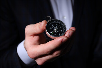 A compass, in the hands of a man, on a dark background.