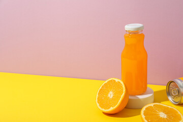 Glass bottle with juice and oranges on pink background, space for text